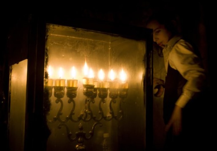 An Ultra Orthodox Jewish boy walks past a menorah at the entrance to his house, after candles were lit on the last night of Hanukkah, in Jerusalem on Wednesday. The Jewish festival of light, an eight-day commemoration of the Jewish uprising in the second century B.C. against the Greek-Syrian kingdom, which had tried to put statues of Greek gods in the Jewish Temple in Jerusalem, started last Wednesday. 